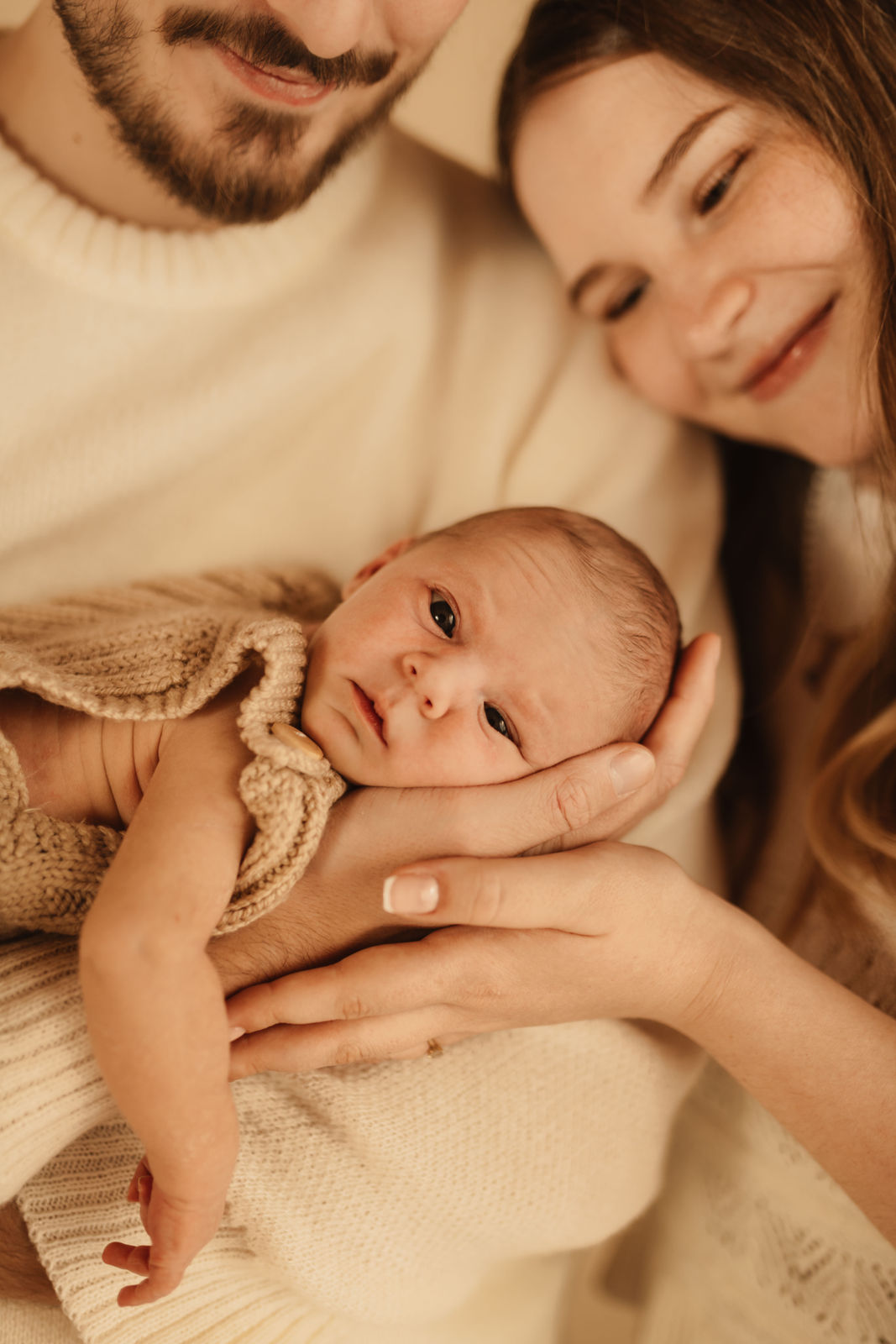 Neugeborenes im Strickbody, geborgen in Mamas Hand